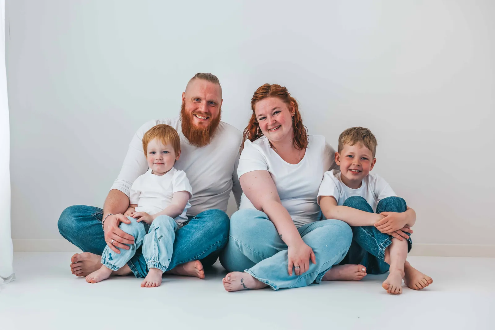 fps-ourfamily En glad familie på fire, der smiler til fotografen – taget af Amalie Sandgaard Photography.